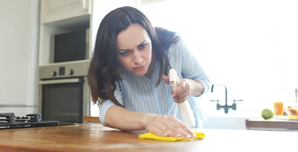 Frau beim Küchenarbeitsplatte reinigen