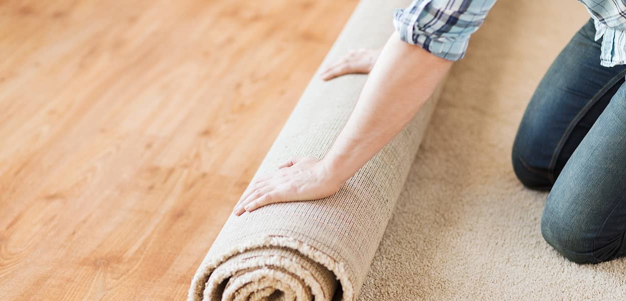 Mann beim Teppich verlegen auf Holzdielen