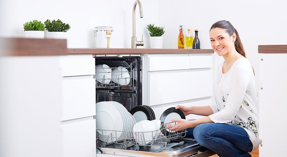 Frau stellt Geschirr in den Spülmaschine