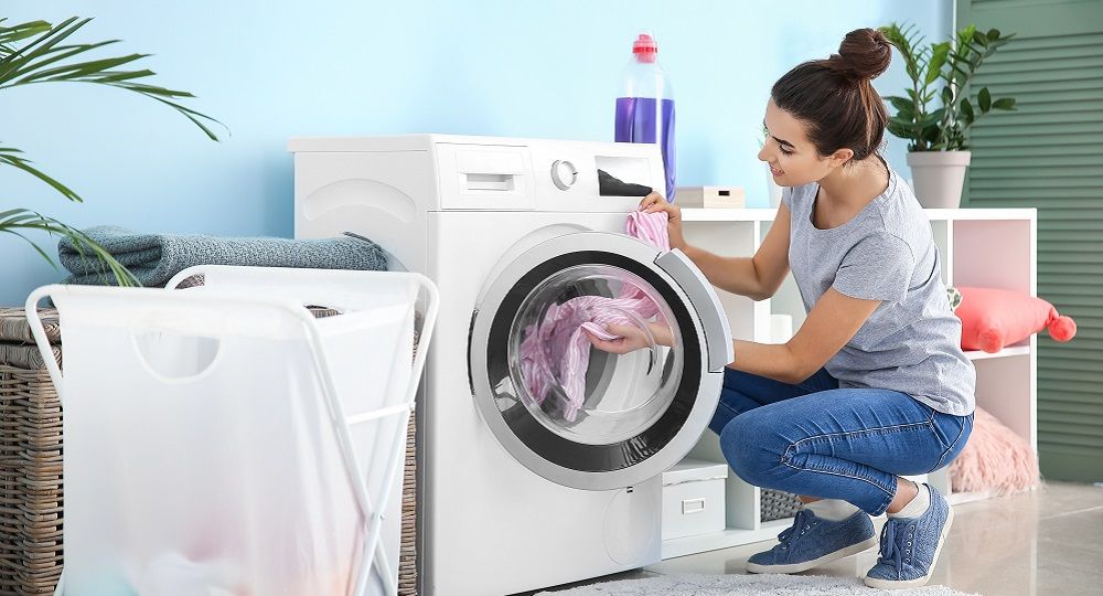 Frau beim Waschmaschine befüllen