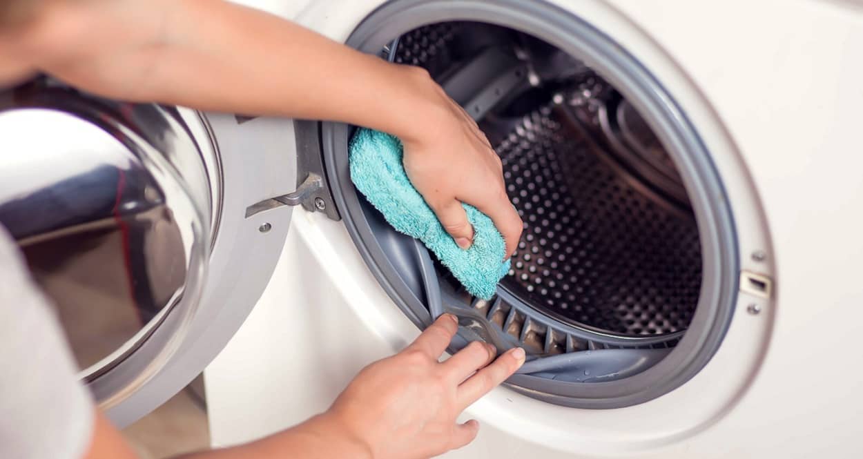 Frau reinigt die Waschmaschine als Vorbeugungsmaßnahme