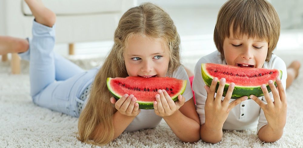Kinder essen Obst auf einem Teppich